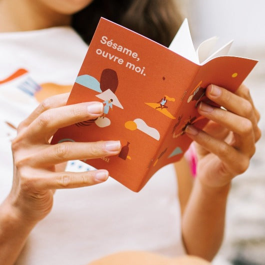 femme lisant son carnet de voyage sésame ouvre moi, de tons terre cuite avec une illustration